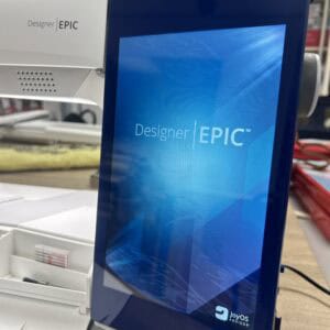 Close-up of a blue Designer EPIC device in a lab, showing the blue screen panel and a white printer/module on the left with Joyos Advisor branding visible at the bottom.