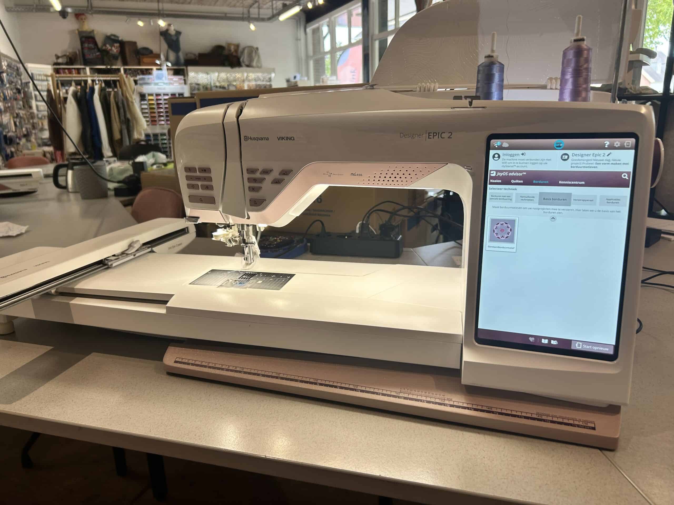 IMG_3680 - Eltink Naaimachines Designer EPIC 2 sewing machine by Husqvarna Viking on a sewing table in a fabric shop, with clothing racks and supplies in the background
