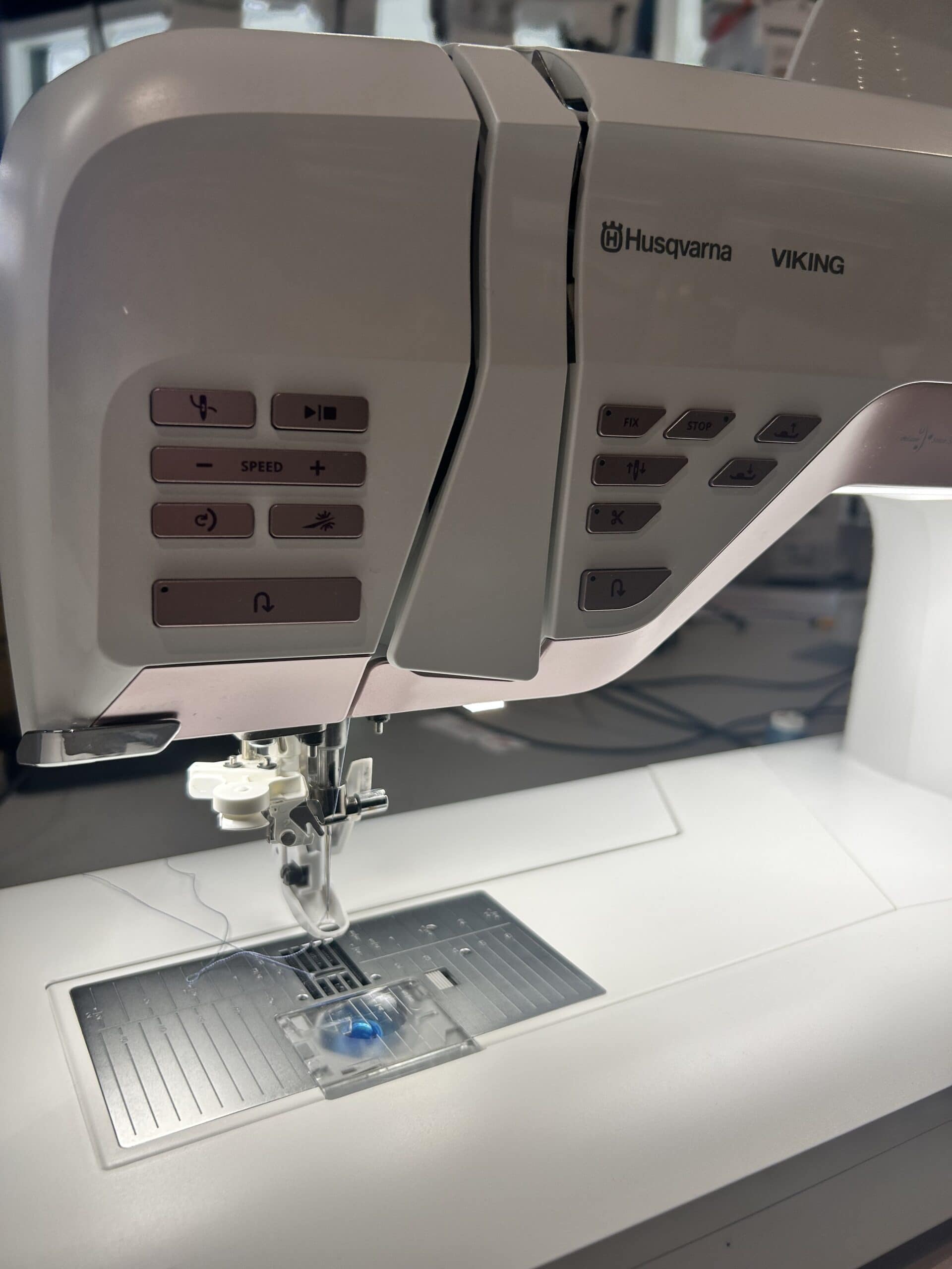 IMG_3682 - Eltink Naaimachines Close-up of a beige Husqvarna Viking sewing machine showing control panel buttons and the presser foot area, with the needle plate visible below.