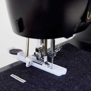 Close-up of sewing machine needle and presser foot over dark fabric, with a white 'PUSH' tab in the foreground.