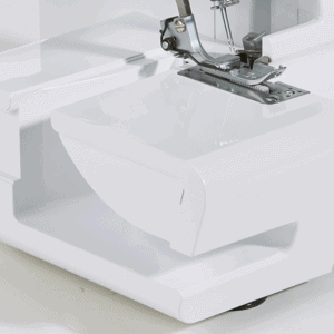 Close-up of a white sewing machine with the needle and metal presser foot ready to stitch on the stitch plate.