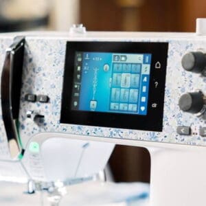 Modern sewing machine with a blue-speckled body and a touchscreen control panel on the front.