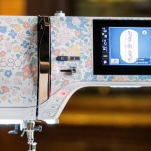 White sewing machine with a blue floral pattern and an attached touchscreen display on the right, model B580
