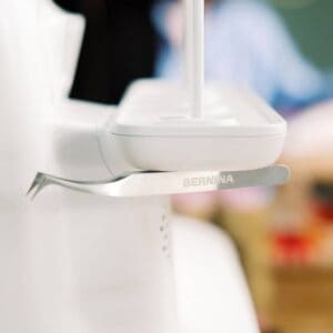 Close-up of a white Bernina sewing machine with a metal presser foot.