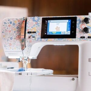 Sewing machine with a colorful floral pattern and touchscreen display, fabric under the needle