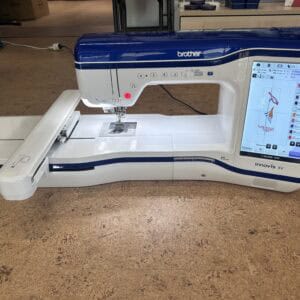 Blue-and-white Brother Innov-is XV sewing machine with touchscreen display visible on the right edge, plugged in on a showroom floor.