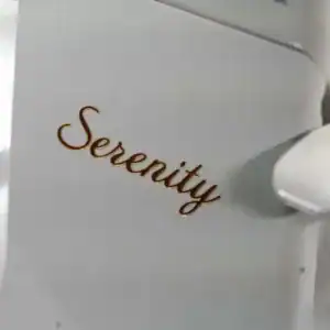 Close-up of a white object with the word 'Serenity' written in brown cursive letters