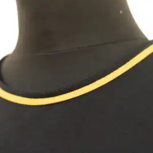 Close-up of a black garment neckline with a thin yellow piping along the edge.
